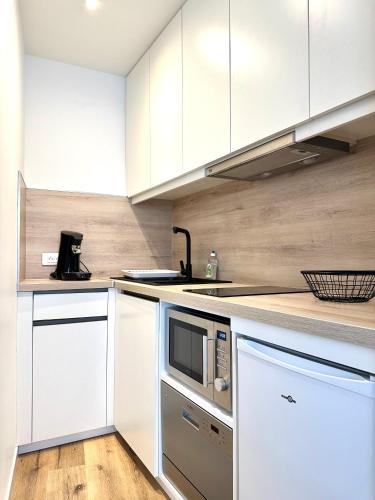 une cuisine avec des armoires blanches et un micro-ondes dans l'établissement Bel appartement en plein centre ville, à Limoges