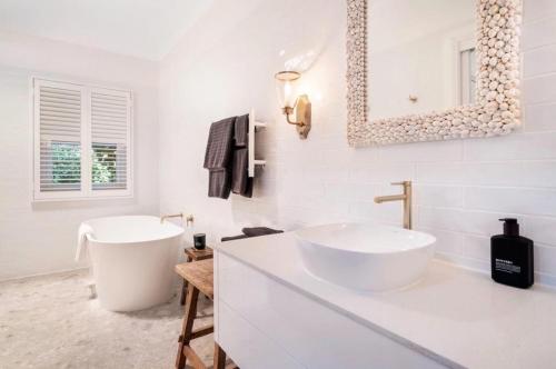 a white bathroom with a sink and a mirror at Beechworth House in Beechworth