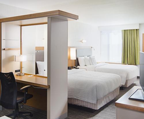 カール・プレイスにあるSpringHill Suites by Marriott Carle Place Garden Cityのベッド2台とデスクが備わるホテルルームです。