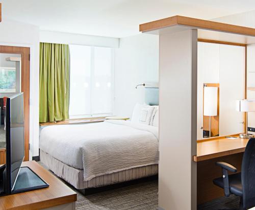 カール・プレイスにあるSpringHill Suites by Marriott Carle Place Garden Cityのベッドとデスクが備わるホテルルームです。
