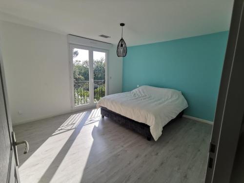 une chambre avec un lit avec un mur bleu dans l'établissement La maison dans la colline, à Velleron