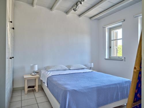 a white bedroom with a bed and a window at Myrto's House seaview of Naxos in Isterni