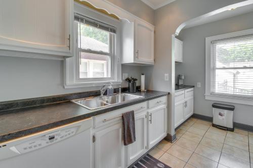a kitchen with white cabinets and a sink and two windows at Charming Springfield Home 2 Mi to Downtown in Springfield