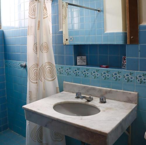 y baño de azulejos azules con lavabo y ducha. en Hotel Calvete en Torreón