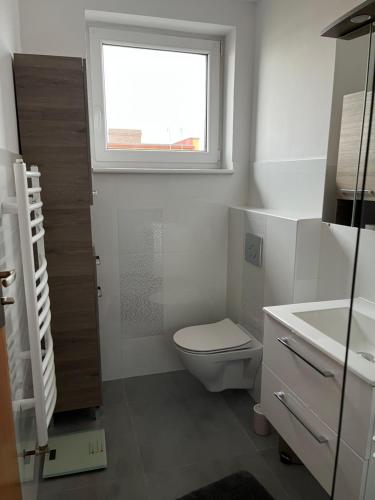 uma casa de banho branca com um WC e uma janela em Apartment beim Lennox em Puck
