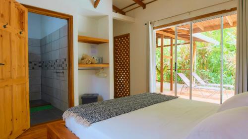 カウイータにあるLa Rana De Cahuitaのベッドルーム1室(ベッド1台付)、スライド式ガラスドアが備わります。