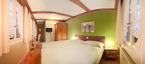a bedroom with a white bed and a green wall at Hotel Hirschen in Langnau im Emmental