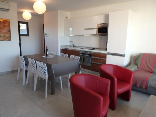 a kitchen and dining room with a table and red chairs at Appartement Cit&eacute; Du Sel in Porto-Vecchio