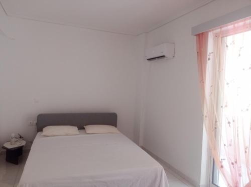 a white bedroom with a bed and a window at Pireas view in Piraeus