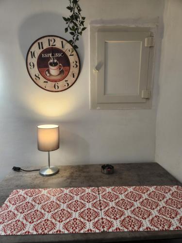 a clock on a wall next to a table with a lamp at Suite SAN GENNARO BIS in Naples