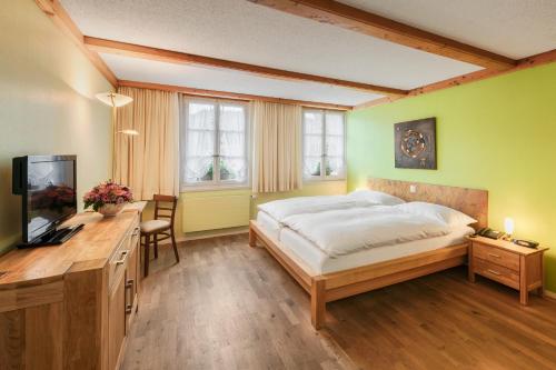 a bedroom with a bed and a desk and a tv at Hotel Hirschen in Langnau