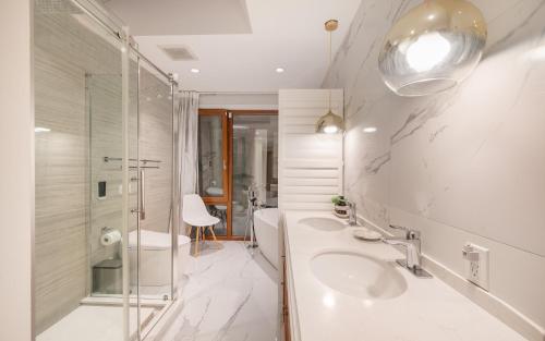 a white bathroom with two sinks and a shower at Lux White Rock Pool House Beachfront Resort like in Surrey