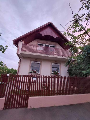 ハイドゥソボスローにあるÁlmos Vendégházの木塀のある小さなピンクの家