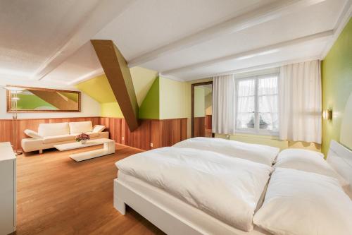 - une chambre avec un grand lit blanc et un canapé dans l'établissement Hotel Hirschen, à Langnau im Emmental
