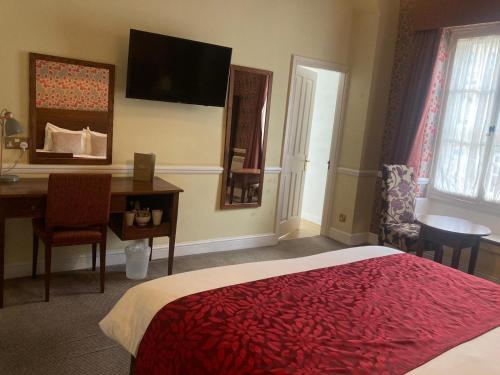 a hotel room with a bed and a desk and a desk at Saracens Head Hotel by Greene King Inns in Towcester