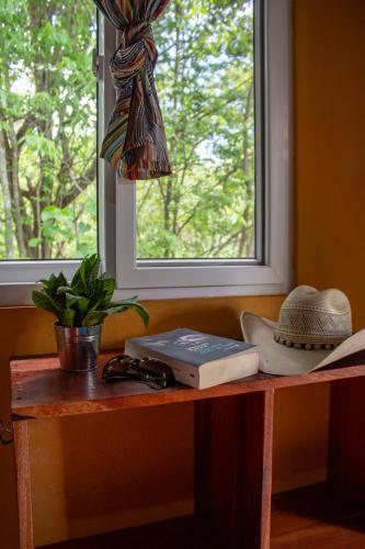 a table with a window with a hat and a book at Alice Guesthouse in El Remate