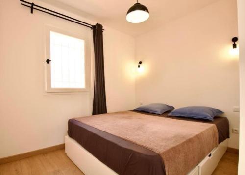 Schlafzimmer mit einem großen Bett und einem Fenster in der Unterkunft Charmante Maisonnette, aux plateaux fleuris in Saint-Laurent-du-Var