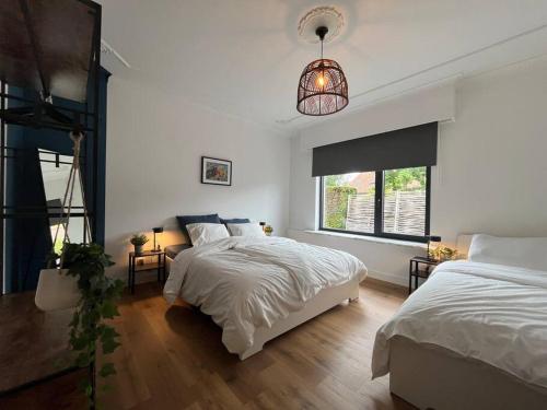 1 dormitorio blanco con 2 camas y ventana en Boldermountain Guesthouse, en Heusden - Zolder
