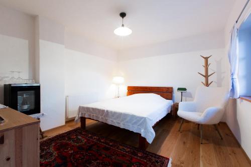 a bedroom with a bed and a chair and a tv at Zimmer am Weinberg in Deutschlandsberg