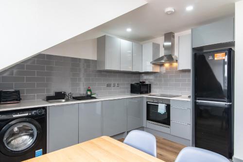 a kitchen with white cabinets and a washer and dryer at 1BR Derby City Centre Flat 5 - Charnwood Flat in Derby