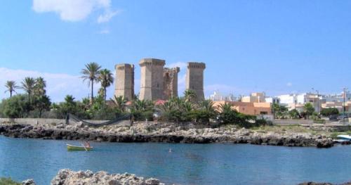 a person in a boat in the water with ruins in the background at Case vacanze LULU in Seclì