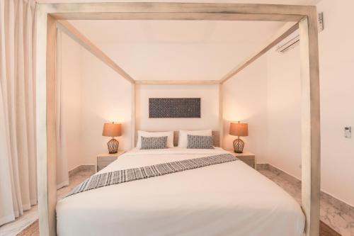 a bedroom with a large white bed with two lamps at Playa Bonita Unique Penthhouse at Lake View in Las Terrenas