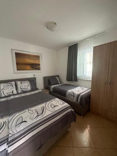 a bedroom with two beds and a cabinet and a window at Apartments Albatross in Novalja
