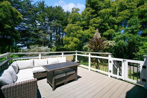 a wooden deck with a couch and a table on a fence at Charming Pet Friendly Coastal Getaway home in Fort Bragg