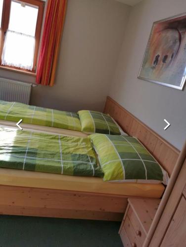 ein Schlafzimmer mit einem Bett mit einer grünen Bettdecke in der Unterkunft Ferienhof Jugendherberge Wurm in Stummerberg