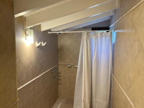 baño con ducha con cortina blanca en Dos Aguas en Tunuyán