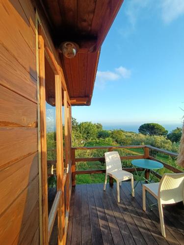 a porch of a cabin with chairs and a table at The Treehouse - Casa sull'albero al Golden Camp in Falerna