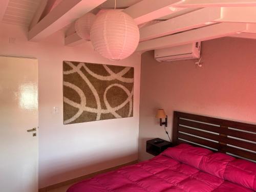 Un dormitorio con una cama roja y una pintura en Dos Aguas en Tunuyán