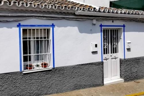 2 ventanas en un edificio blanco con adornos azules en La Marieta, casita acogedora y centrica, en Castilleja de la Cuesta