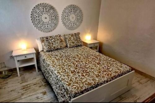 a bedroom with a bed with two tables and two lamps at La Marieta, casita acogedora y centrica in Castilleja de la Cuesta