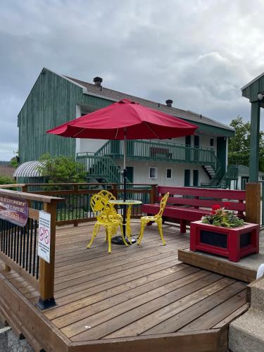a wooden deck with a picnic table and an umbrella at Hotel Le Pionnier in Tadoussac
