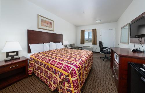 Habitación de hotel con cama y TV de pantalla plana. en America Inn & Suites, en Ridgecrest