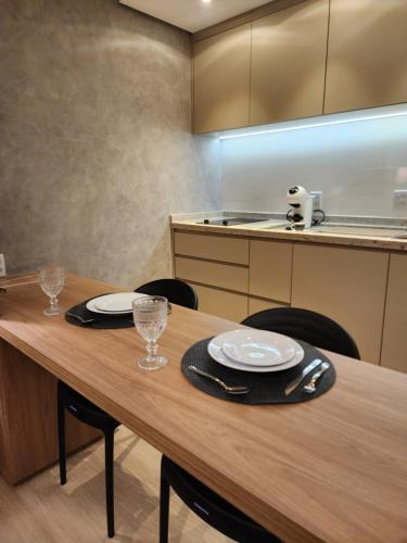 a kitchen with a wooden table with plates and glasses at Fabuloso Blend Setor Marista in Goiânia