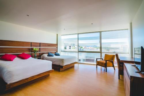 a bedroom with two beds and a desk and a television at Millenium Plaza & Suites in San Luis Potosí