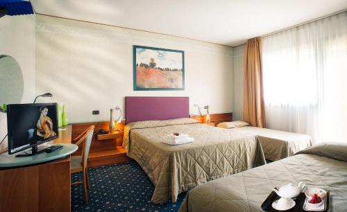 Pasiano di PordenoneにあるIl Cecchiniのベッド2台とテレビが備わるホテルルームです。