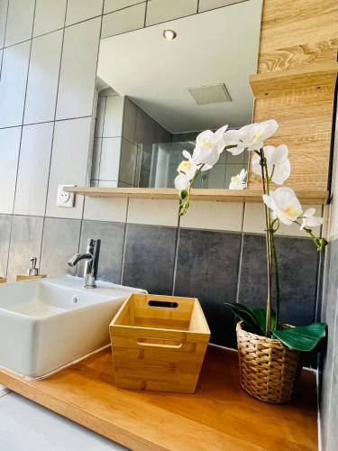 - une salle de bains avec un lavabo et des fleurs blanches dans un panier dans l'établissement SUPERBE DUPLEX DESIGN NEUF 2 CHAMBRES, CLIMATISE TOUT CONFORT, FACILE D,ACCES STATIONNEMENT GRATUIT, à Marseille