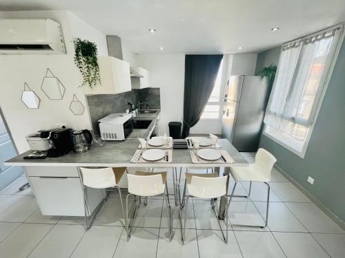 - une cuisine avec une table et des chaises blanches dans l'établissement SUPERBE DUPLEX DESIGN NEUF 2 CHAMBRES, CLIMATISE TOUT CONFORT, FACILE D,ACCES STATIONNEMENT GRATUIT, à Marseille