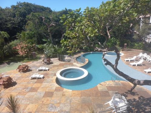 a swimming pool in a yard with chairs and trees at Ubaia charme & conforto in Pipa
