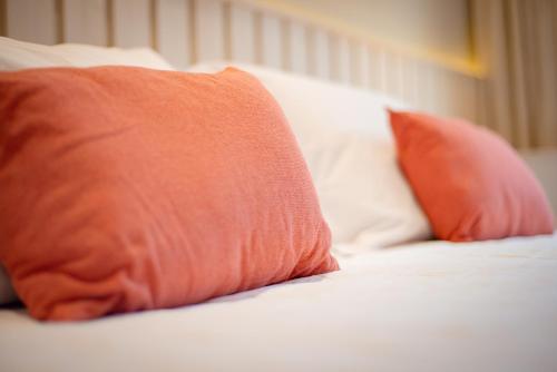 a bed with two orange pillows on it at Pousada Xica in Fernando de Noronha