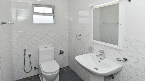 La salle de bains blanche est pourvue de toilettes et d'un lavabo. dans l'établissement Roseberry Villa, à Nuwara Eliya