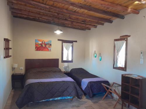 2 camas en una habitación con techos de madera en Cabañas Cañones del Triásico en Villa Unión