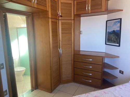 ein Schlafzimmer mit einem Holzschrank und einem WC in der Unterkunft Cobertura de frente para o Mar in Caraguatatuba
