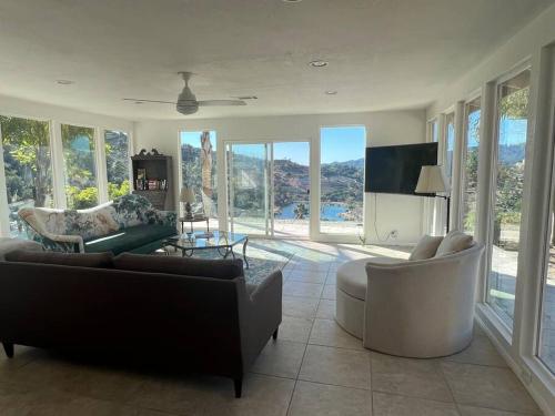 sala de estar con sofás, sillas y ventanas en The most breathtaking Lake and Mountain View en Fallbrook