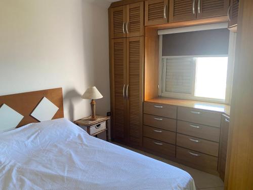 ein Schlafzimmer mit einem Bett, einem Fenster und einer Kommode in der Unterkunft Cobertura de frente para o Mar in Caraguatatuba