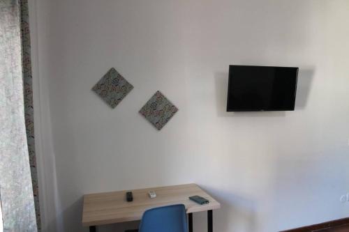 Una habitación con una mesa y un televisor en una pared. en Alexander House, en Palermo