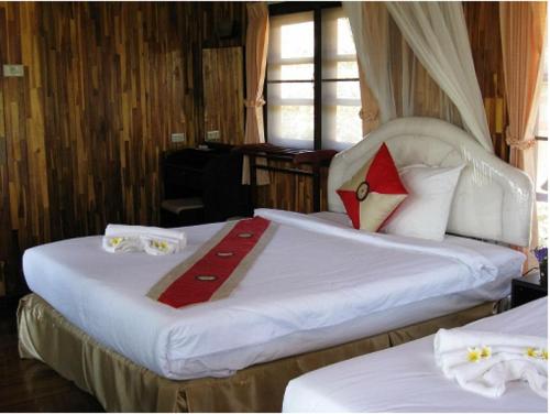 a bedroom with two beds with white sheets and red pillows at Busai Country View in Wang Nam Khieo